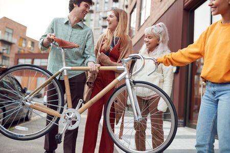 Group Of Multi-Cultural Friends On City Street Lifting Sustainable Bamboo Bicycleの写真素材