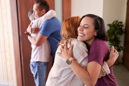 Couple Greeting Senior Parents At Front Door As They Come To Visitの写真素材