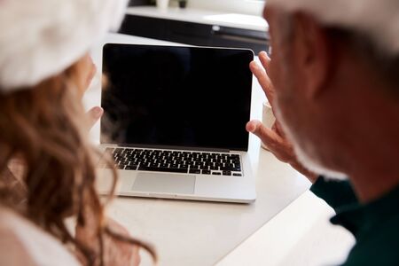 Senior Hispanic Couple Wearing Santa Hats With Laptop Having Video Chat With Family At Christmasの写真素材