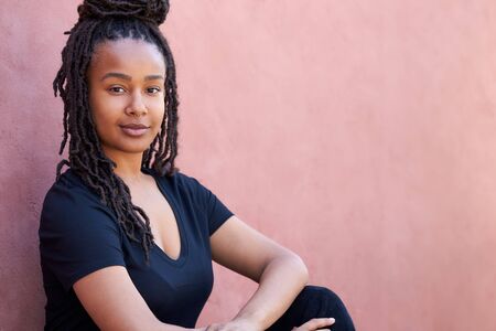 Outdoor Head And Shoulders Portrait Of Attractive Young Woman Leaning Against Wall In The Street