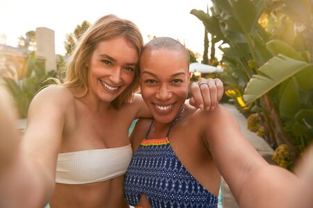 Two Female Friends At Summer Pool Party Taking Selfie On Mobile Phone