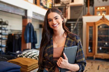 Portrait Of Smiling Female Owner Of Fashion Store Standing In Front Of Clothing Displayの写真素材