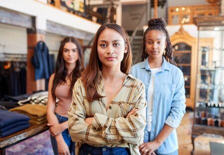 Portrait Of Multi-Cultural Female Sales Team In Fashion Store Standing In Front Of Clothing Displayの写真素材