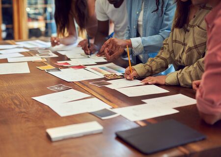 Close Up Of Team Having Creative Design Meeting Around Wooden Table In Office