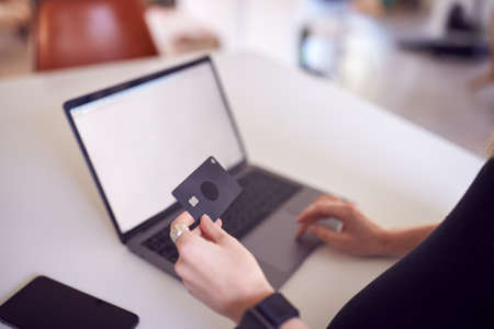 Close Up Of Woman In Kitchen Making Online Credit Card Purchase On Laptopの写真素材