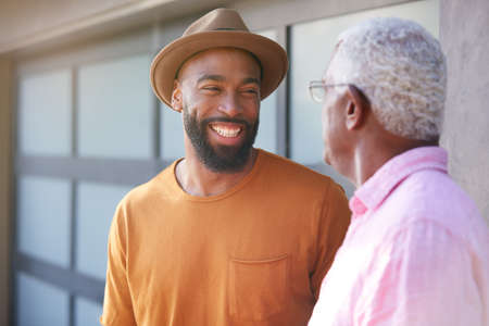 Senior Father Talking And Laughing With Adult Son In Garden At Homeの写真素材