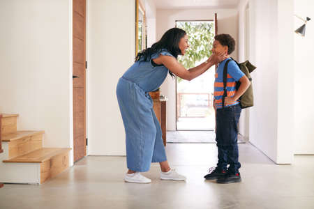 Mother Saying Goodbye To Son As He Leaves Home For Schoolの写真素材