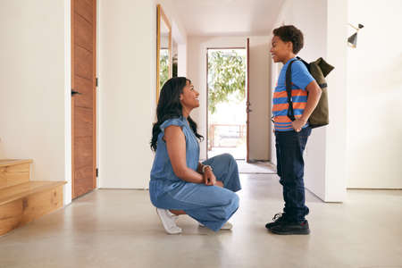 Mother Saying Goodbye To Son As He Leaves Home For Schoolの写真素材