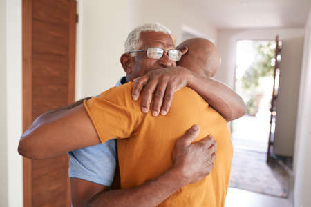 Loving Senior Father Hugging Adult Son Indoors At Homeの写真素材