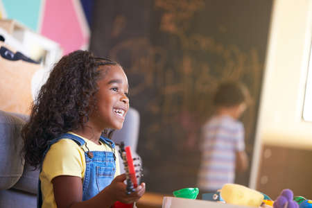 Young Girl Having Fun Playing Toy Guitar In Room At Home