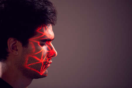 Facial Recognition Technology Concept As Man Has Red Grid Projected Onto Face In Studioの写真素材