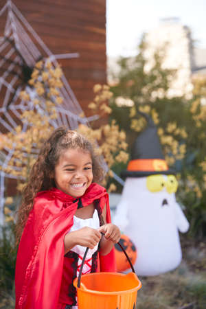 Girl Wearing Fancy Dress Outside House Collecting Candy For Trick Or Treat
