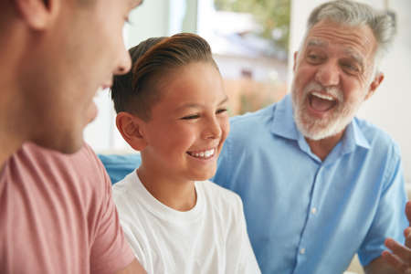 Multi-Generation Male Hispanic Family Relaxing On Sofa At Home Together