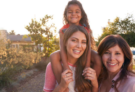 Portrait Of Female Multi-Generation Hispanic Family Relaxing In Garden At Home Togetherの写真素材