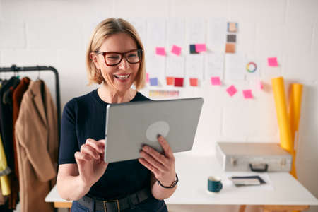 Mature Businesswoman Using Tablet Computer In Studio Of Start Up Fashion Businessの写真素材