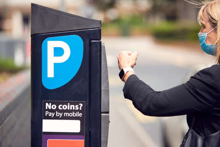 Businesswoman Wearing PPE Face Mask Makes Contactless Payment For Car Parking With Smart Watch