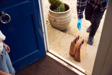 Close Up Of Food Delivery Driver Putting Takeaway On Doorstep Outside Houseの写真素材