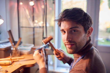 Portrait Of Smiling Male Jeweller At Bench Working In Studioの写真素材