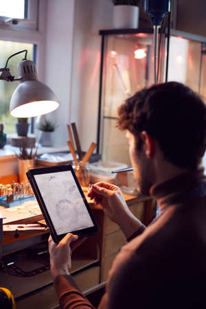 Close Up Of Male Jeweller Looking At Ring Design On Digital Tablet In Studioの写真素材