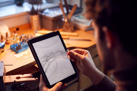 Close Up Of Male Jeweller Looking At Ring Design On Digital Tablet In Studioの写真素材