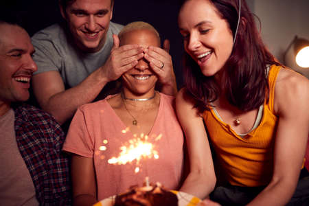 Group Of Friends Meeting To Celebrate Womans Birthday At Home Surprising Her With Cake