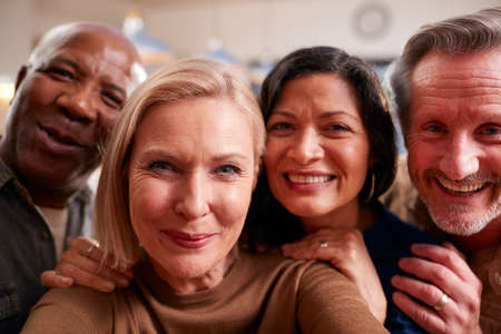 Group Of Mature Friends Posing For Selfie On Mobile Phone At Home