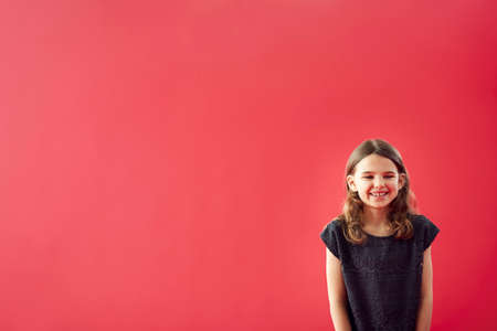 Portrait Of Girl Against Red Studio Background Smiling At Camera