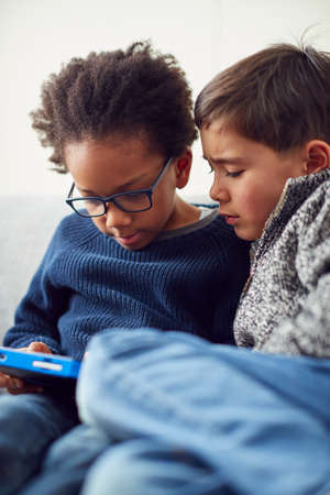 Two Boys Gaming Together On Hand Held Devices At Homeの写真素材