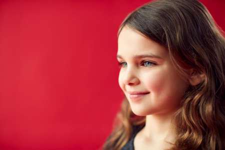 Portrait Of Girl Against Red Studio Background Smiling At Cameraの写真素材