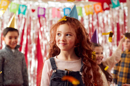 Group Of Children In Party Hats Celebrating At Birthday Party With Streamers And Gold Confettiの写真素材