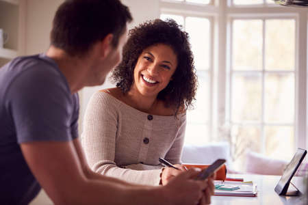 Couple With Digital Tablet Working From Home On Kitchen Counter