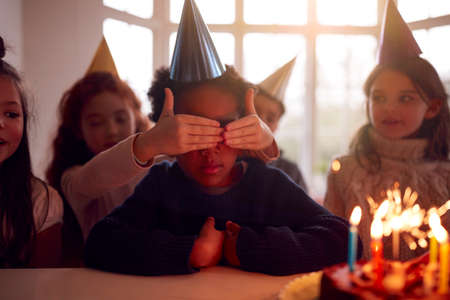 Boy Celebrating Birthday With Group Of Friends At Home Being Given Cake Decorated With Sparkler
