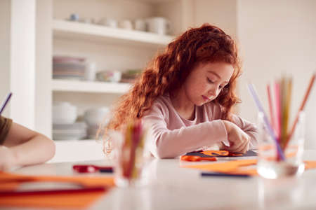 Girl At Home With Friends Having Fun Making Halloween Decorations Together
