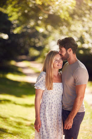 Loving Couple Hugging As They Walk Along Countryside Path In Summer Togetherの写真素材