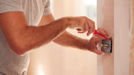 Close Up Of Electrician Fitting Light Switch At New Build Propertyの写真素材