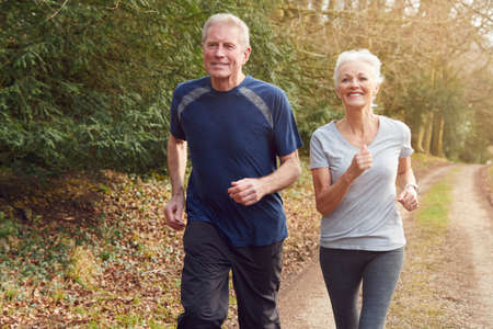 Senior Couple Exercising In Autumn Countryside During Covid 19 Lockdown