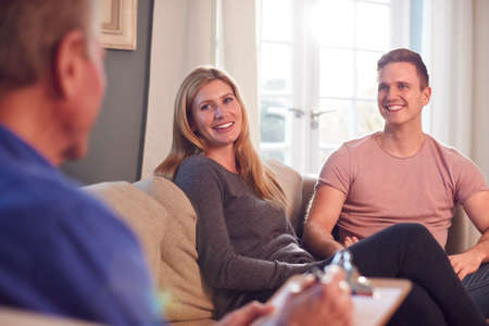 Male Social Worker With Clipboard Visiting Young Couple At Homeの写真素材