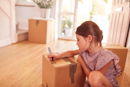Girl Labelling Boxes Getting Ready For Moving Day Into New Home
