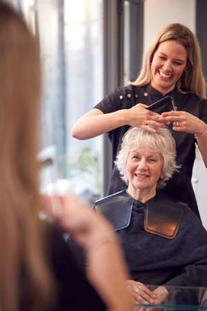 Senior Woman Having Hair Cut By Female Stylist In Hairdressing Salonの写真素材