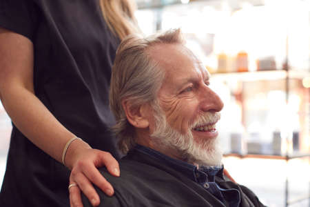 Senior Man Having Hair Cut By Female Stylist In Hairdressing Salonの写真素材