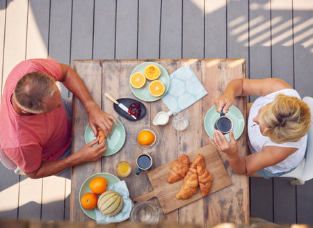 Overhead Shot Of Retired Couple Outdoors On Deck At Home Eating Breakfastの写真素材