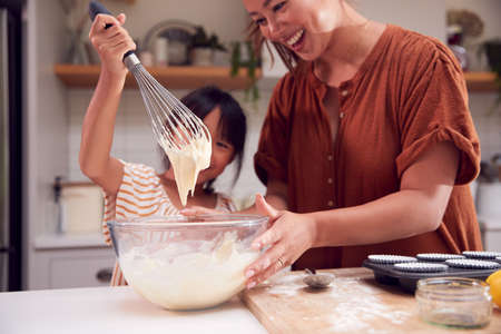 Asian Mother And Daughter Making Cupcakes In Kitchen At Home Togetherの写真素材