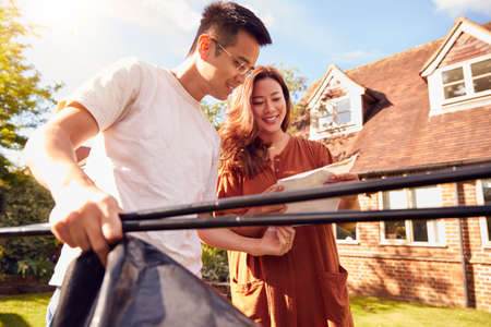 Asian Couple In Garden At Home Putting Up Tent For Camping Trip Togetherの写真素材
