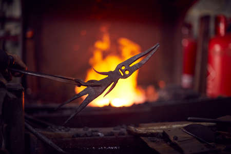 Close Up Of Male Blacksmith Cooling Metalwork In Water After Taking Out Of Forge