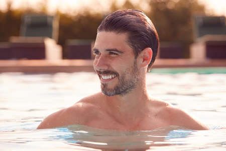 Smiling Man Relaxing On Summer Vacation In Outdoor Swimming Poolの写真素材