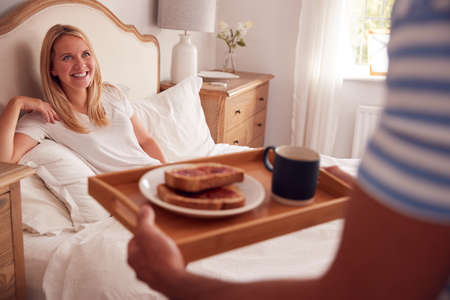 Husband Surprising Wife With Breakfast In Bed At Homeの写真素材