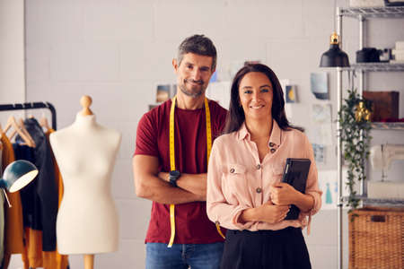 Portrait Of Male And Female Fashion Designers With Tape Measure And Digital Tablet In Studioの写真素材