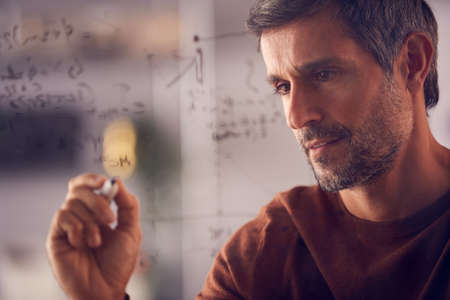 Brainstorming Businessman Or Mathematician Drawing Graph Calculation On Glass Screen In Office