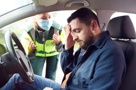 Female Paramedic Helping Male Driver With Whiplash Neck Injury Involved In Road Traffic Accidentの写真素材