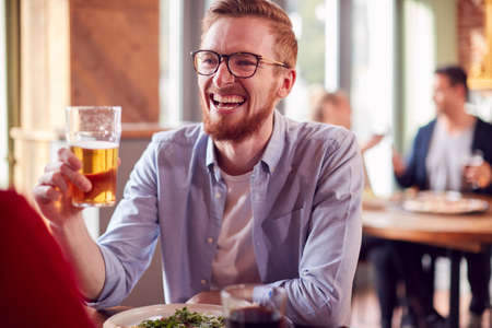 Smiling Young Couple On Date Making Toast Before Enjoying Pizza In Restaurant Togetherの写真素材